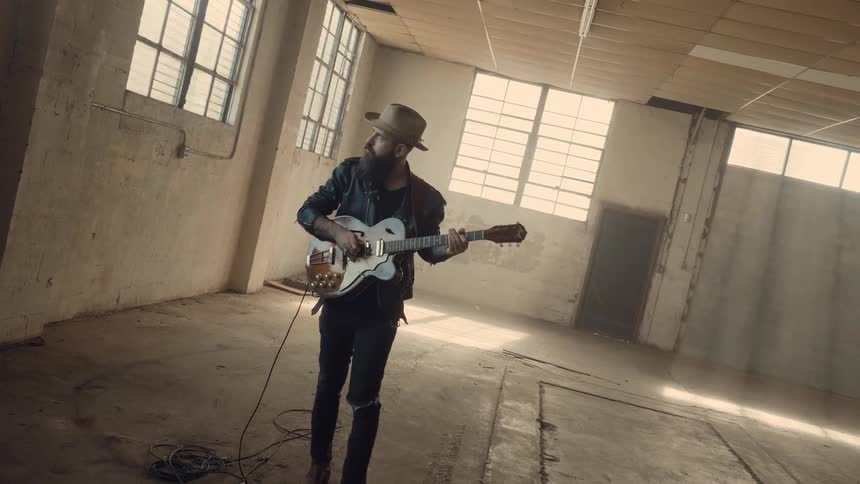 Guy plays the electric guitar in an abandonded building