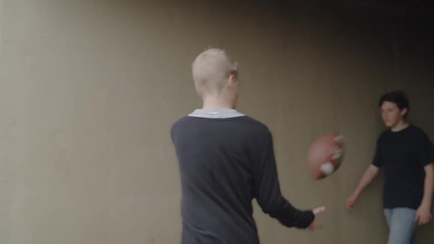 Kids toss around a football while walking out of an overpass