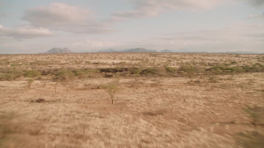A barren landscape is stretching out towards hills on the horizon in daylight
