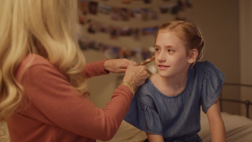 A mother braids her daughters hair