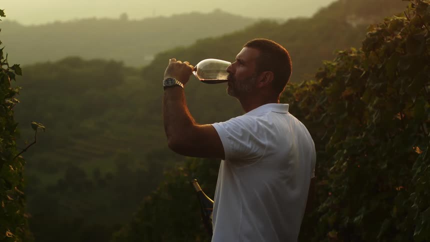 A man takes a drink from a glass on the hill