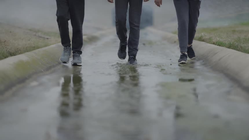 Three people walk down a slim canal