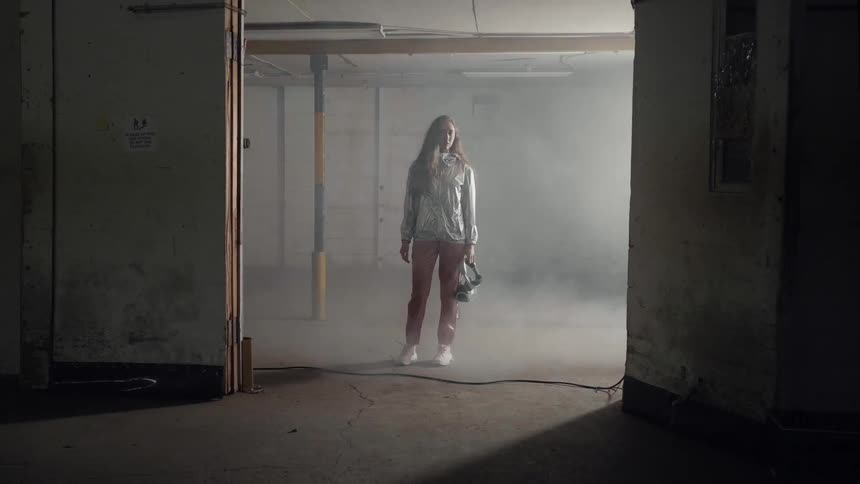 A woman stands in a warehouse with flashing lights