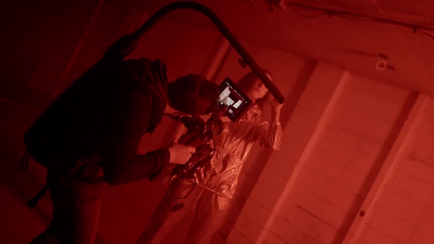 A man is filming a woman as she dances inside an abandoned building