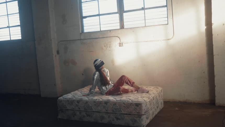 Girl sits on a mattress in an abandoned building