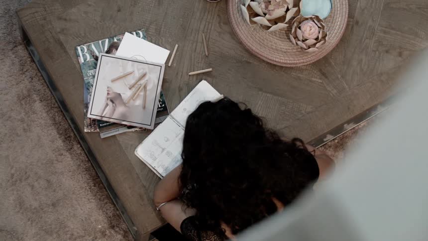 A woman is sitting at a table indoors looking at a notebook