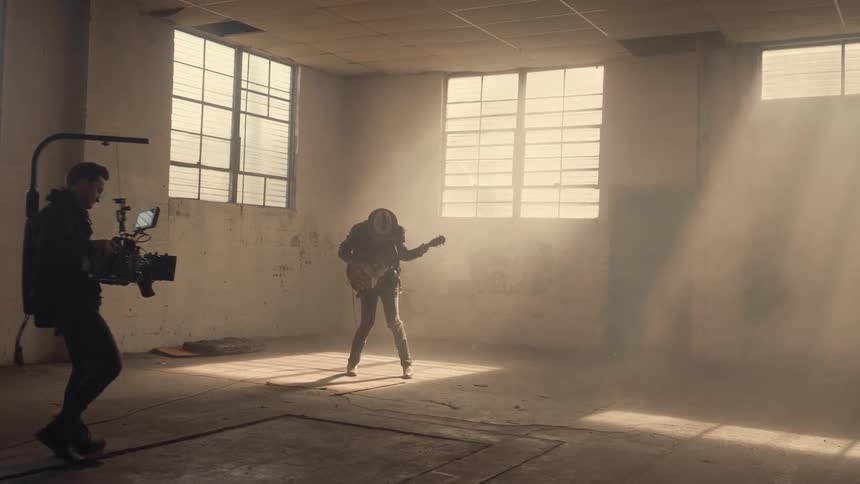 A guitar player is being filmed in the large room