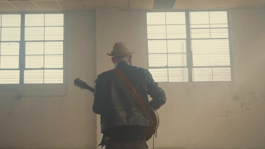 Man playing guitar in a large empty room of a building