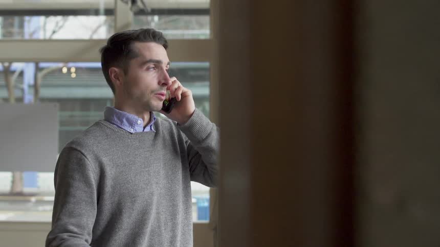 Man stands in office talking on the phone