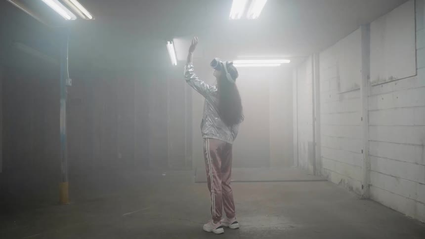 A woman is standing inside an abandoned warehouse wearing a vr headset