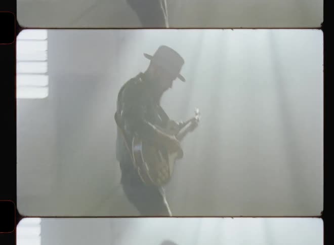 A man plays guitar inside a dusty warehouse