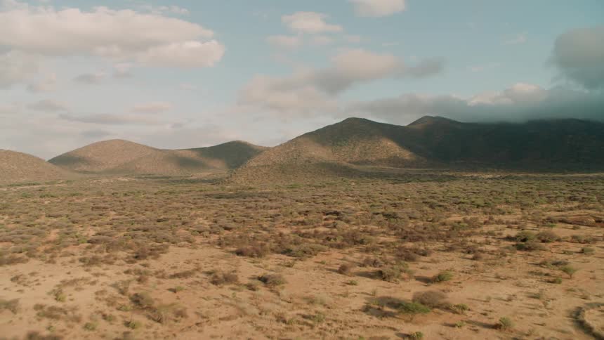 The desert leads to hills in the distance