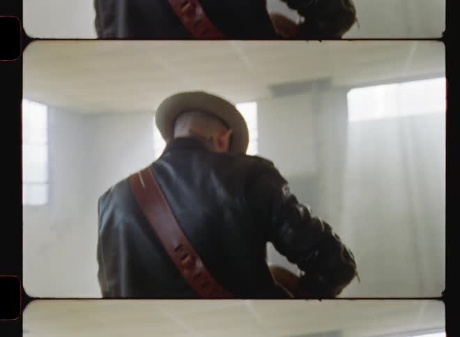 A man walks forward in the room playing a guitar