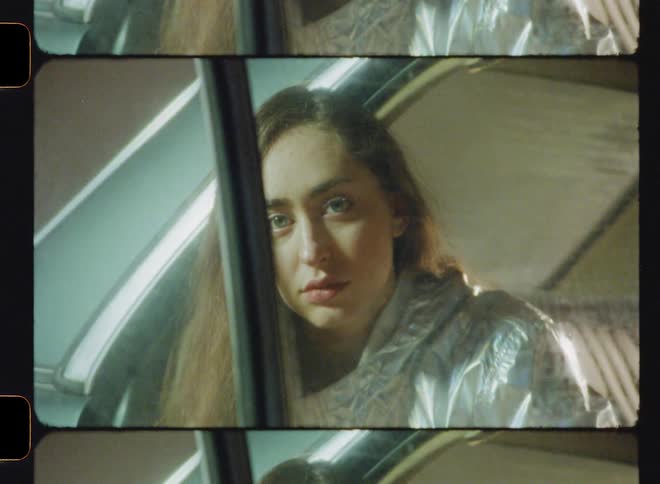 A woman is sitting with the door open in a car parked inside a building