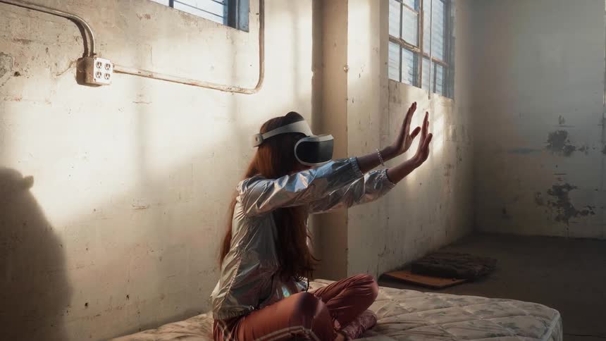 A woman sits on a mattress using a vr headset
