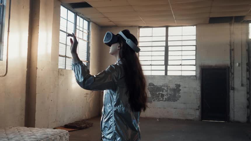 The woman looks around moving her hands wearing a virtual reality headset