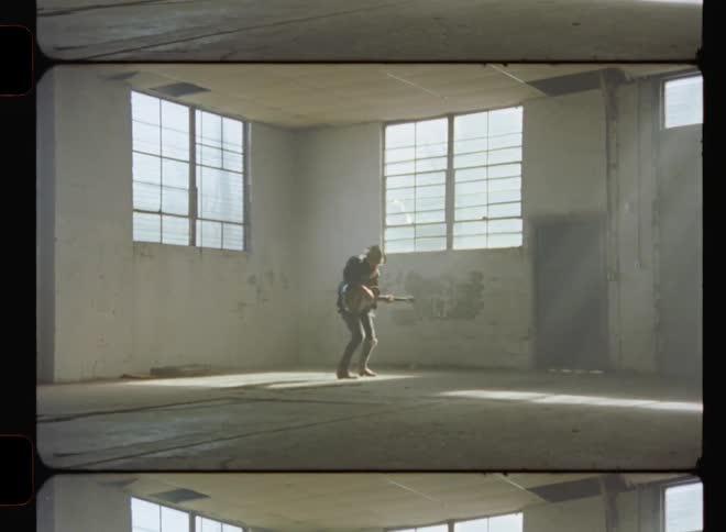 Man swinging and playing guitar in empty building