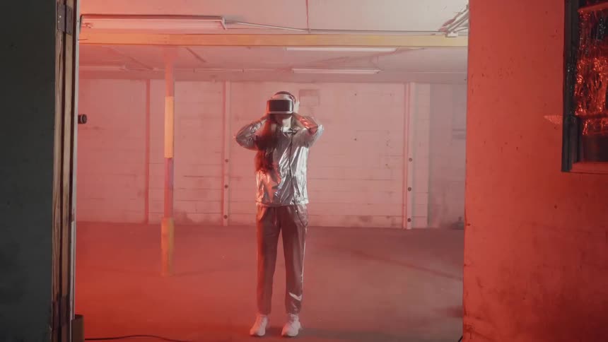 A woman wears a virtual reality headset in a warehouse with flashing lights