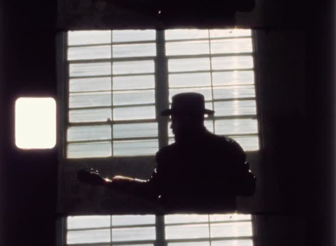 Man silhouetted in a room playing a guitar