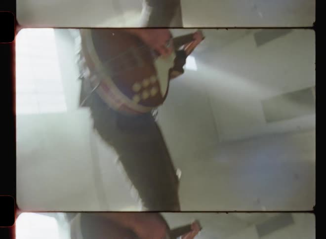 A man plays a semi-hollow body guitar in an empty room