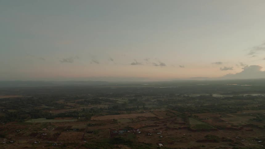 Passing over farmland and buildings at sunset
