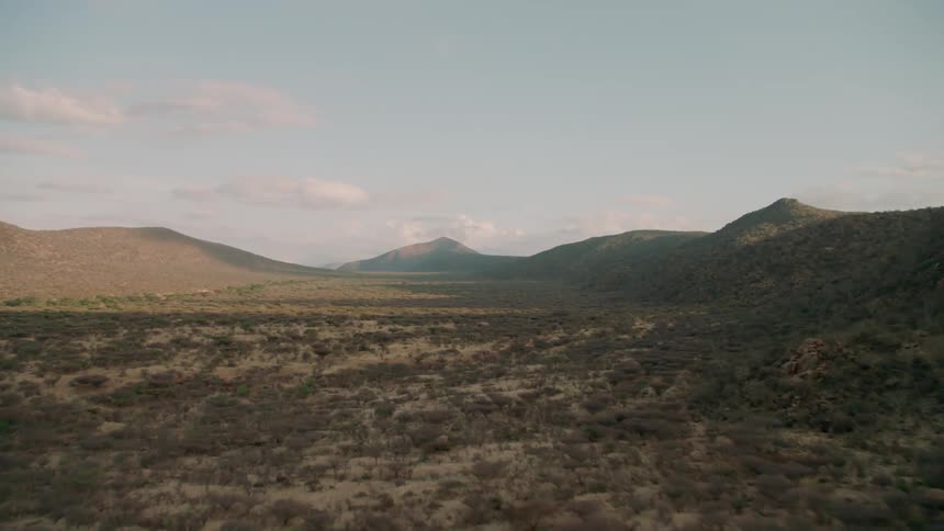 The desert leads to hills in the distance