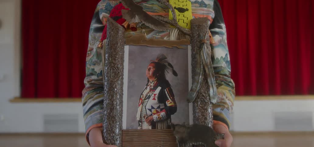 The woman is holding a portrait of a man