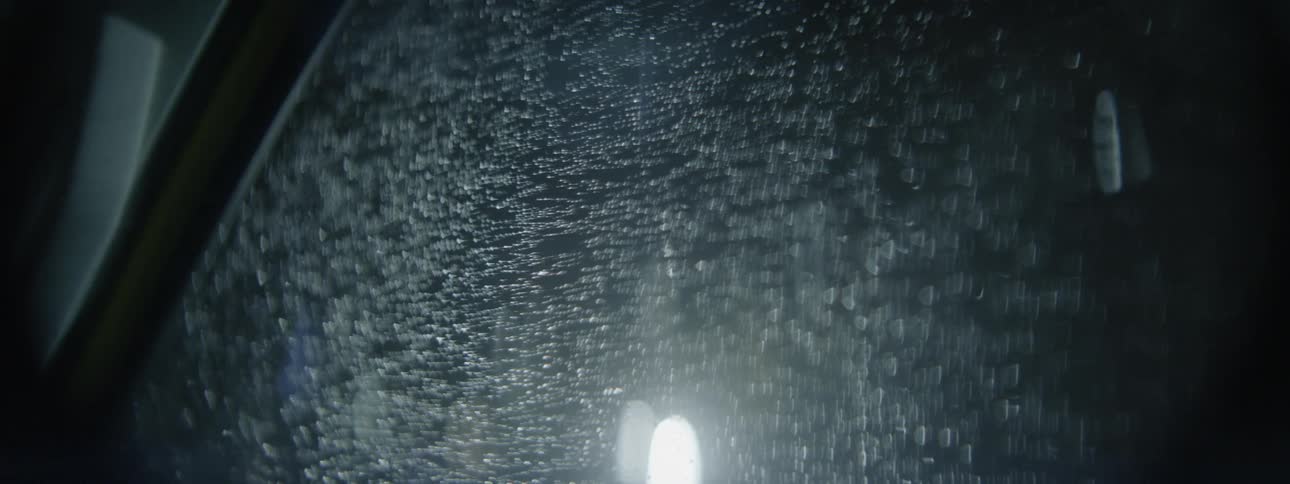 A vehicle is driving at night in the rain