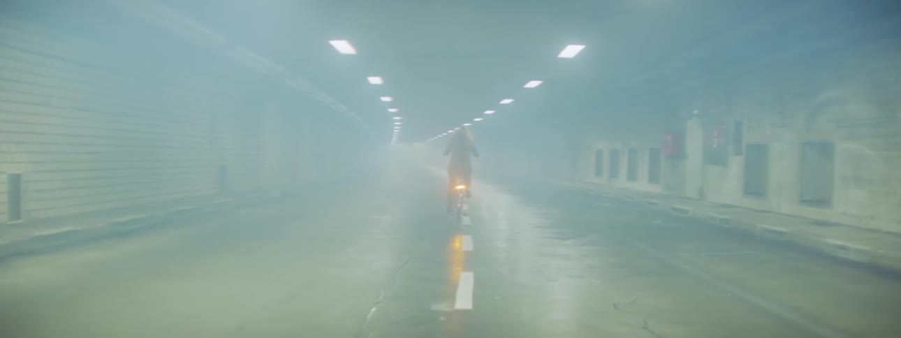 A person rides a bike through a smoky tunnel