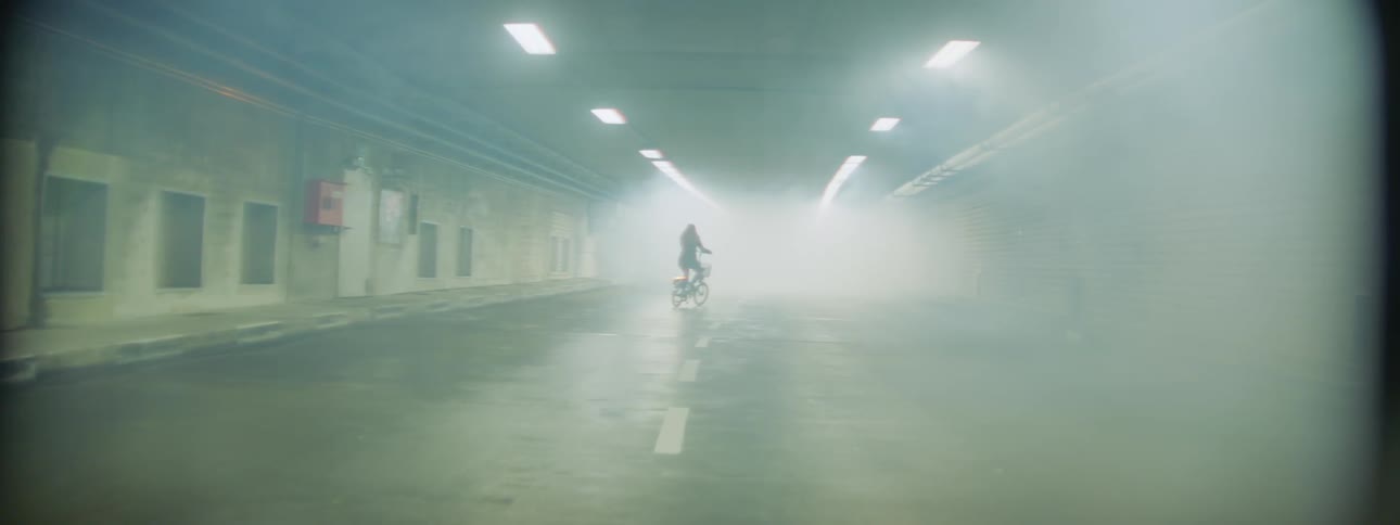 A woman is riding a bicycle in a foggy tunnel