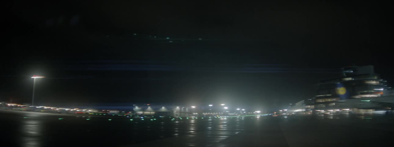 A vehicle drives on an airport tarmac at night