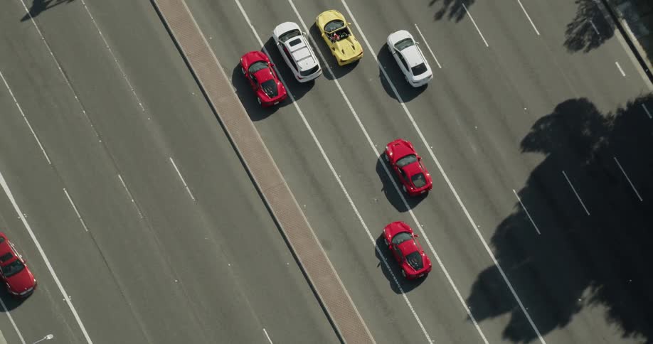Bird's eye view of Lamborghinis and Ferraris driving in Los Angeles