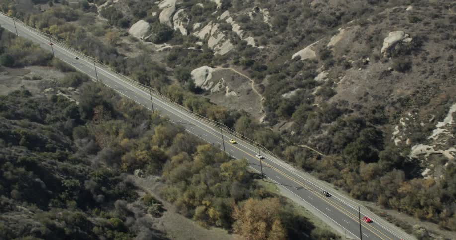 Lamborghinis and Ferraris race through a desert mountain landscape