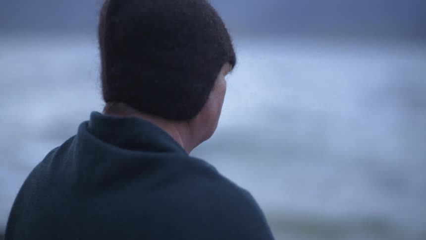 A person is standing and watching the sea in daylight