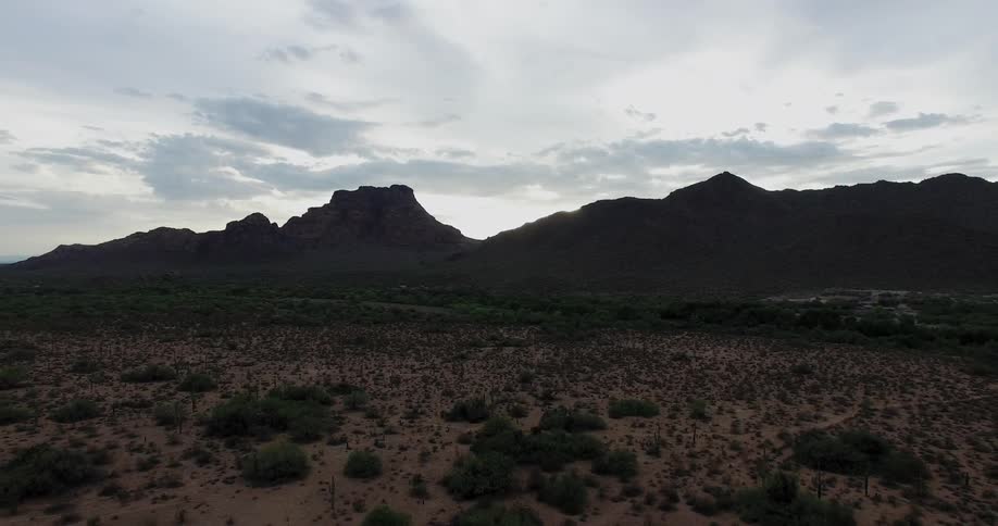 Sun sets over rocky hills and brush covered land