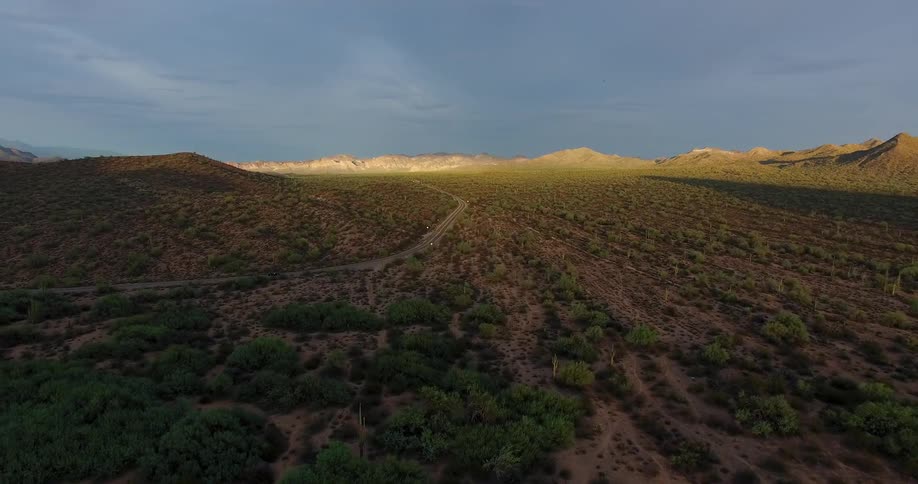 A road cuts through the desert landscape beneath a cloudy sky