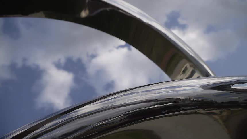 Clouds hang above a chrome structure