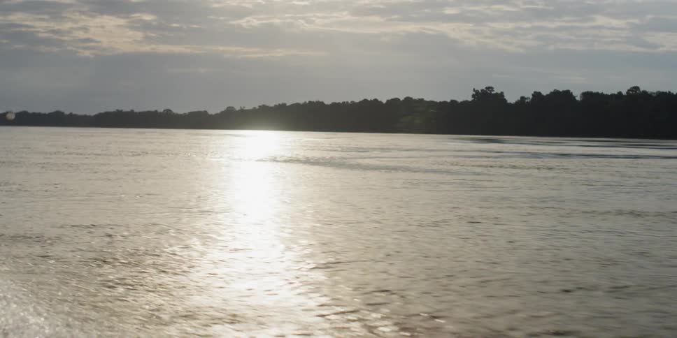 Sun reflects off a tree lined lake