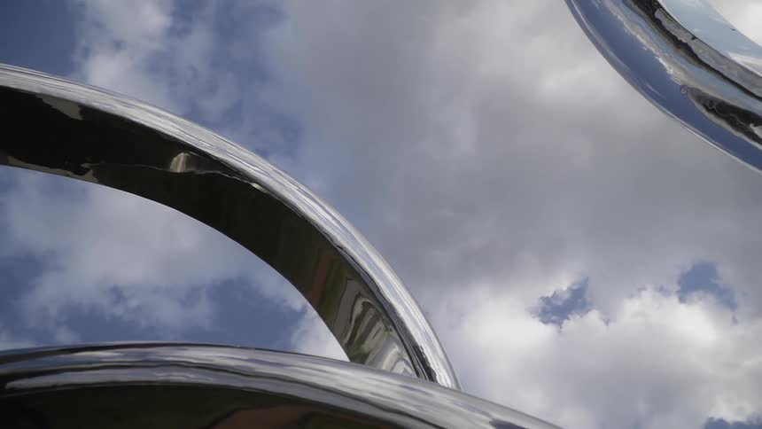 Clouds are hovering in the sky over a metal artwork