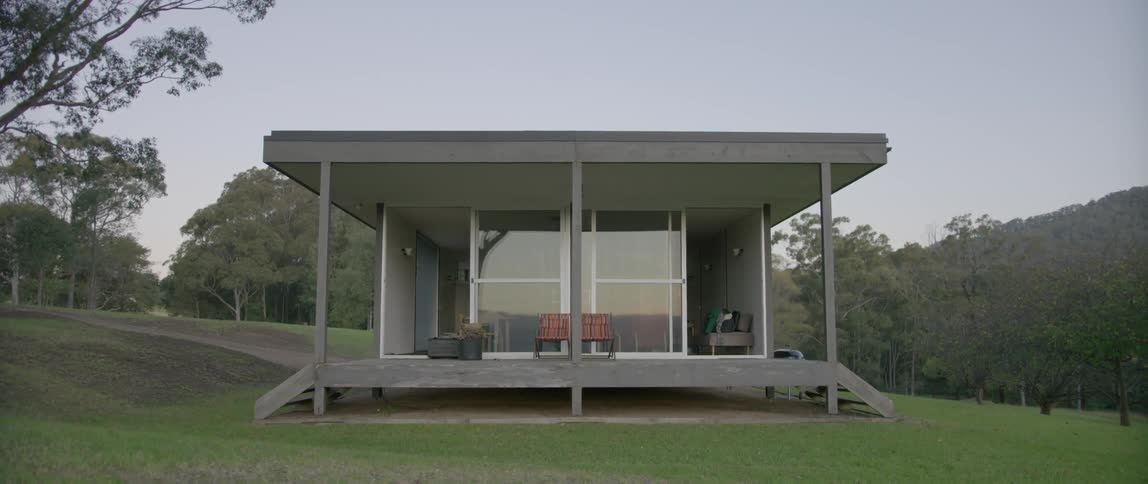 A modern-looking open-air apartment sits isolated in a grassy field