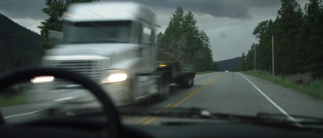 A car is driving down the road on a cloudy day