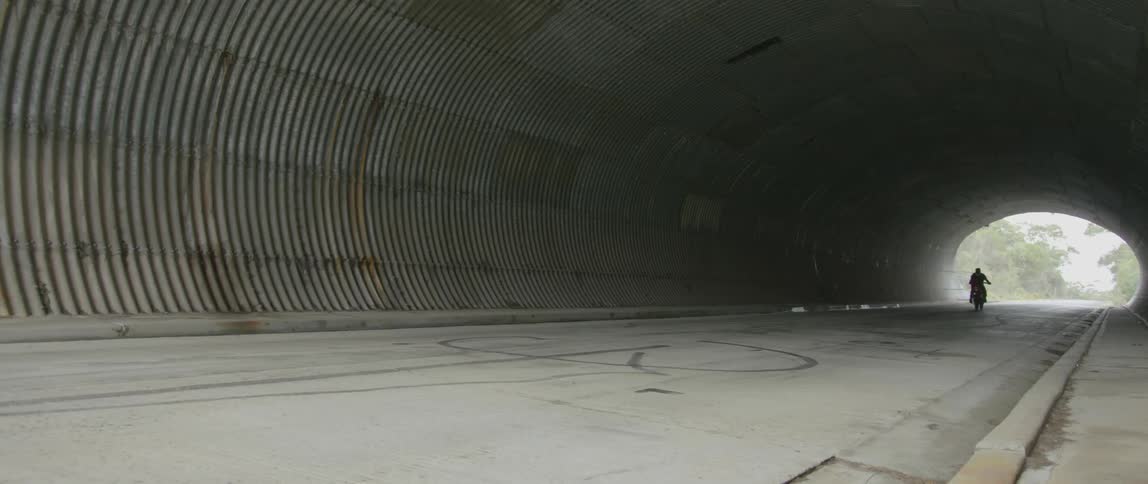 Man riding his motorcycle through a large tunnel