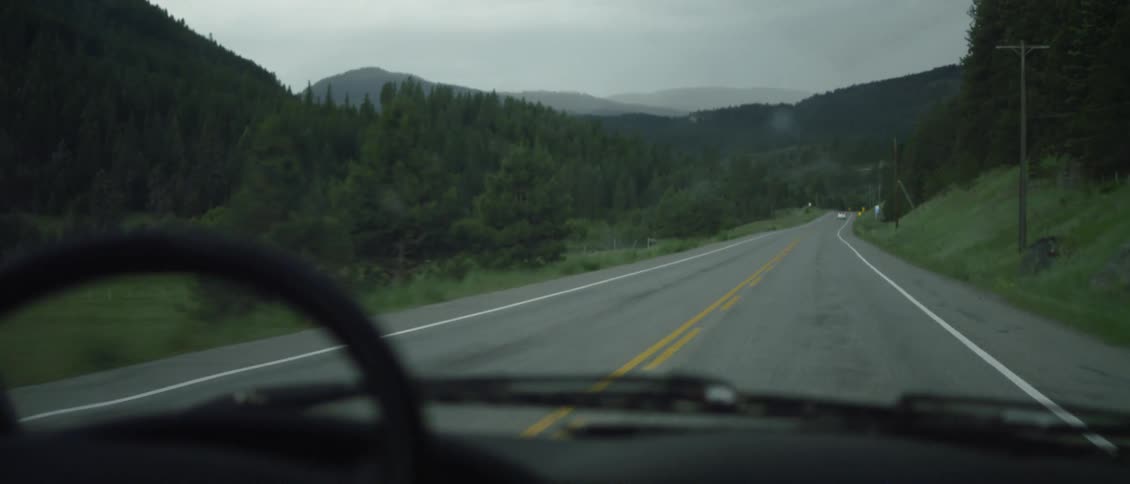 The car drives down the single lane road