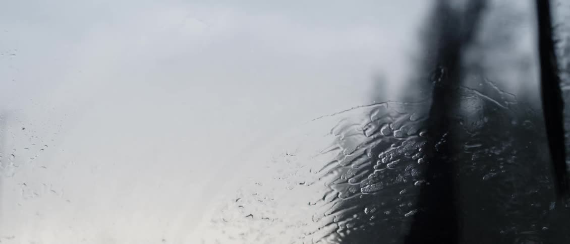 Wiper blades on a windshield is wiping away the rain