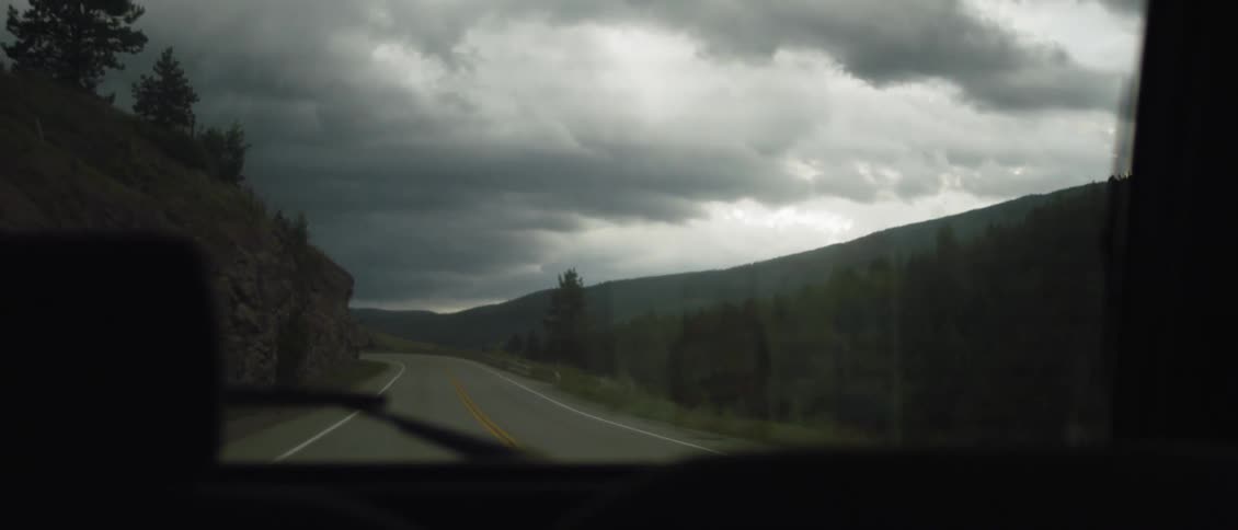 Storm clouds over the landscape through the car's back window