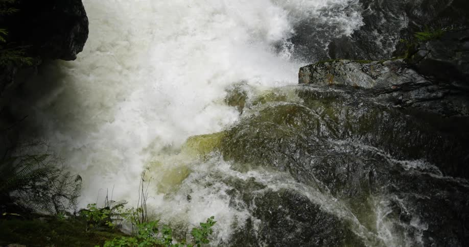 Water flowing over a rocky waterfall and into a basin of a river