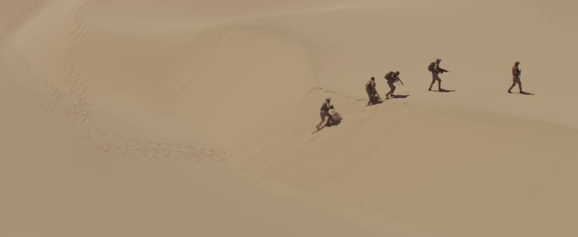 Soldiers march over the desert on a sunny day