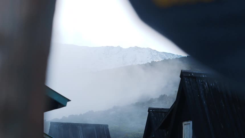 Fog rushing up a mountain next to a village