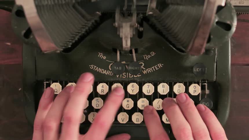 A person is typing fast on an old typewriter