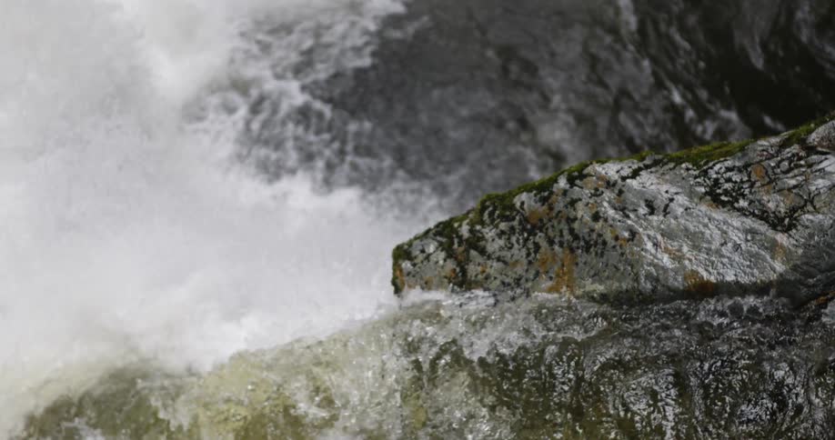 Water is cascading over boulders down a precipice in daylight